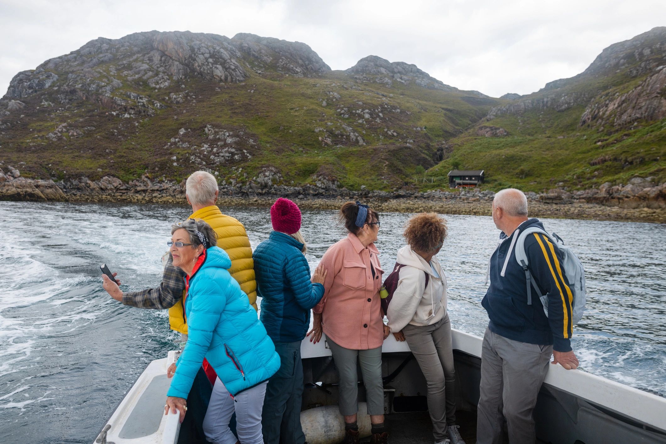 Travelers on a shore excursion boat approaching a scenic coastline